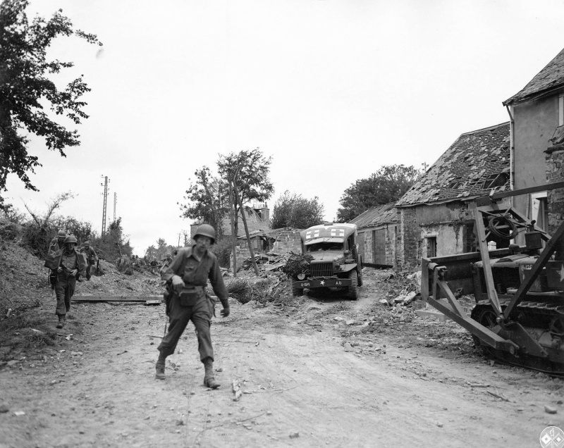 Американские солдаты проходят мимо санитарного автомобиля Додж WC54 и бульдозера Caterpillar R4 «Tilt Dozer» по улице разрушенного французского городка Ла Э-дю-Пюи (La Haye-du-Puits).